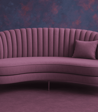 Curved plum velvet sofa with ribbed backrest, gold legs, and accent cushion in a modern purple-toned interior.